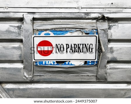 No parking sign on old worn metallic garage door