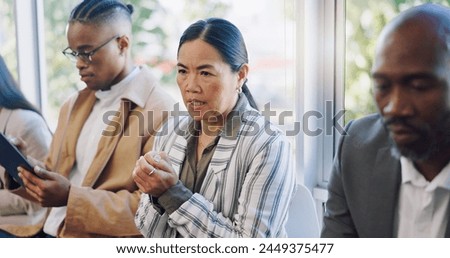 Anxiety, interview and woman in waiting room with candidates at recruitment agency. Human resources, hiring and fear, men and women in lobby with hope, motivation and stress for new job opportunity. Royalty-Free Stock Photo #2449375477