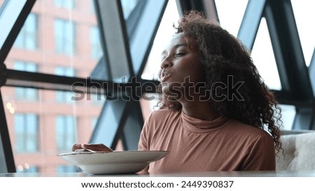 Such delicious tasty filling food. Close-up of a curly-haired beautiful woman tasting food in a new restaurant.