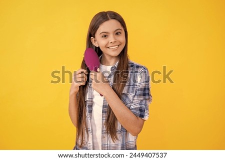 happy teen girl holding hairbrush and brushing hair. teen girl brushing long hair with hairbrush. Beautiful teen girl with hairbrush. teen girl using a hairbrush to style her hair isolated on yellow