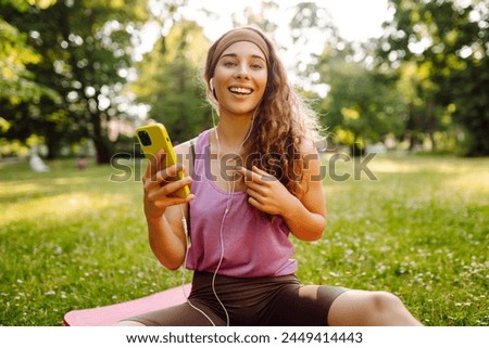 Young sports female with smartphone for progress, performance and communication for a healthy lifestyle.  Sport, Active life, healthy lifestyle. Royalty-Free Stock Photo #2449414443