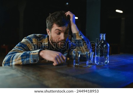 It was a hard day. Depressed young man drinking vodka in bar. Royalty-Free Stock Photo #2449418953