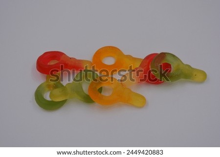 Unusual and non-standard colored jelly green, yellow, red, yellow, orange candies in the form of a key arranged on a white plastic background. Royalty-Free Stock Photo #2449420883