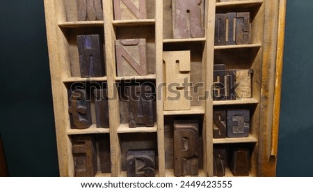 A vintage printing press box filled with different types of letterpress letters, carved into each one. The aged and weathered wood still showcases its history as an early 