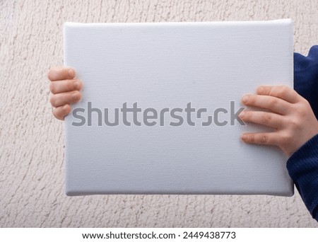 Little kid holding a blank canvas board in hands. Copy space for text.