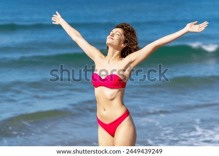 Happy slim woman in bikini with raised arms