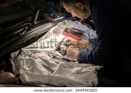 Male mechanics at the garage fixing a car Royalty-Free Stock Photo #2449445805