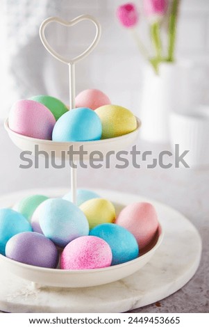 Colorful easter eggs on a cake stand on a kitchen table. Color mood bright, pastel, fresh and harmonious.