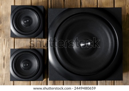 Large cubic subwoofer in a wooden cabinet with metal grille and two audio speakers on a background of natural pine boards. Audiophile concept. Audio system 2.1. Photo. Close-up Royalty-Free Stock Photo #2449480659