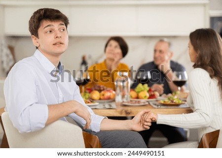 Upset young guy at family holiday table with parents at home. Unpleasant discussion Royalty-Free Stock Photo #2449490151