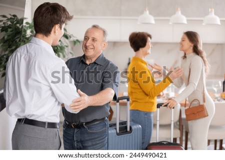 Hospitable parents joyfully welcome their adult children who have come to visit from far away Royalty-Free Stock Photo #2449490421