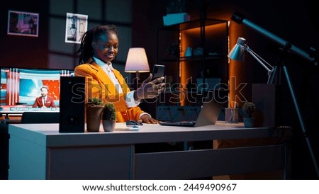 Young woman waving at phone videocall with tutor and classmates, asking for guidance in creating presentations and slideshows. African american student attending online class conference. Camera B. Royalty-Free Stock Photo #2449490967