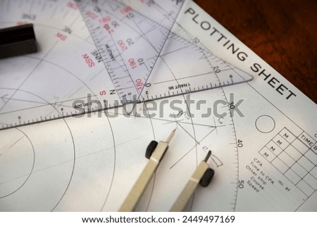 Above image of a navigator's radar plotting chart with a triangler and compass divider and a calculated angle