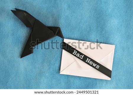 Black raven paper origami carrying white envelope letter with word Bad News. Deliver and bearer of bad news concept. Royalty-Free Stock Photo #2449501321