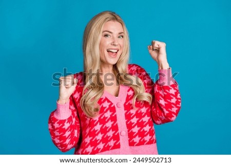 Portrait of optimistic person with curly hairdo dressed knitwear jumper raising up fists win betting isolated on blue color background