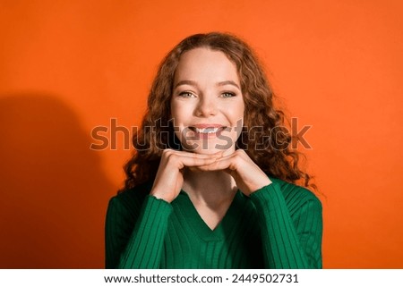 Photo of sweet pretty lady dressed green shirt hands arms chin emtpy space isolated orange color background Royalty-Free Stock Photo #2449502731
