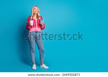 Full size photo of smart person wear knit cardigan hold cappuccino smartphone look at promo empty space isolated on blue color background