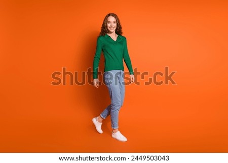 Full length photo of excited funky lady dressed green shirt walking empty space isolated orange color background