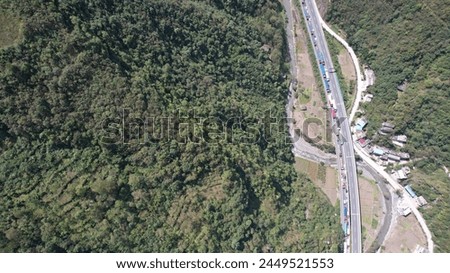 An ultra-high-definition aerial photo captures a congested highway winding through the mountains, illustrating the challenging blend of nature and human transportation.