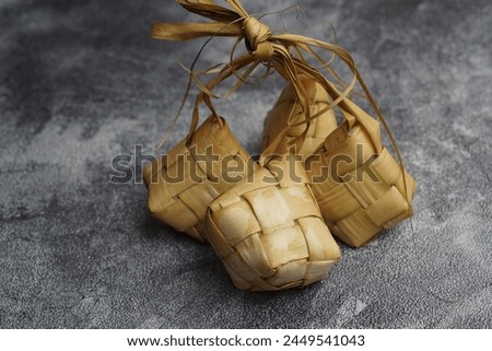 Close up view of Ketupat, an Indonesian traditional cuisine very popular during Hari Raya Idul Fitri served on a wooden table. This is made of the white rice, usually served with opor ayam on Ied day. Royalty-Free Stock Photo #2449541043