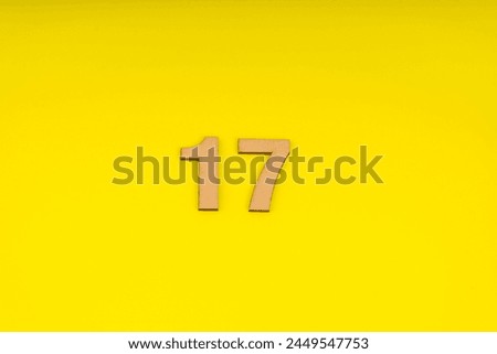 Number Seventeen in leather on yellow background Royalty-Free Stock Photo #2449547753