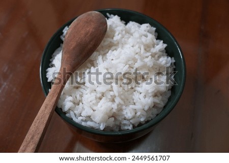 One bowl of white rice and wooden spoon on brown wooden table, food, stock photo.
