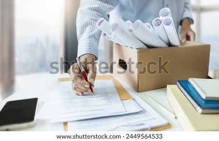 Asian men packing roll of personal documents into a box reading and sign resignation letter for resign from work. concept for quit and find a new job