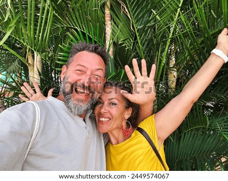 Adult youthful couple taking selfie picture together with green park leaves in background smiling and having fun in front of the phone camera. Tourist lifestyle people concept. Leisure activity