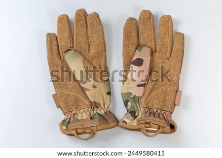 Pair of the green-brown tactical military gloves made with textile and synthetic leathern on a gray background
 Royalty-Free Stock Photo #2449580415