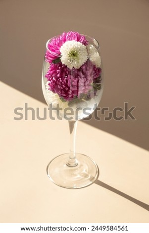 Wine glass full of colorful flowers. Creative concept for holidays greeting card postcard. Minimalistic isometric style. Drinking beauty bouquet 