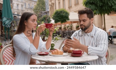 Young frustrated disappointed woman upset offended drinking coffee city outside cafe Caucasian separated man busy mobile phone telephone lack of attention ignoring couple relationship problem breakup Royalty-Free Stock Photo #2449584647