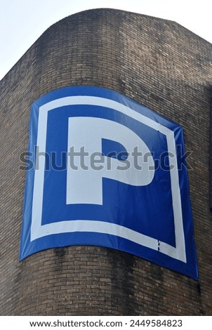 Large Temporary Parking Sign on Brick Wall of Car Park seen from Below 