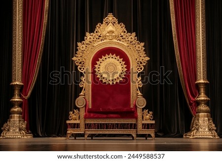 A large, ornate throne with gold accents and rich red velvet cushions sits on an empty stage in front of black curtains.  Royalty-Free Stock Photo #2449588537