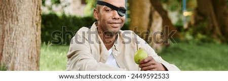 A blindfolded African American man holds an apple, symbolizing diversity and inclusion in society.