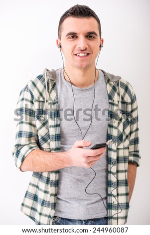 Casual young man with mobilephone and  headphone, on grey background.