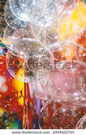 A large number of transparent plastic bubbles floating in the air. The balls are in a colorful red-yellow room, creating a visually attractive and playful atmosphere Royalty-Free Stock Photo #2449602765