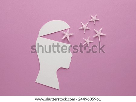Paper-cut open human head with sea stars on pink background. Travel concept