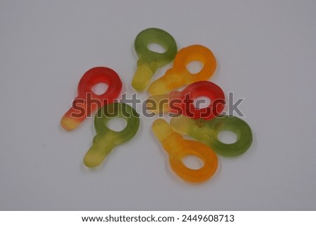 Unusual and non-standard colored jelly green, yellow, red, yellow, orange candies in the form of a key arranged on a white plastic background. Royalty-Free Stock Photo #2449608713