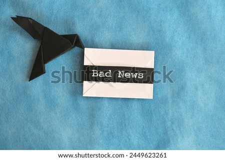 Black raven paper origami carrying white envelope letter with word Bad News. Deliver and bearer of bad news concept. Royalty-Free Stock Photo #2449623261
