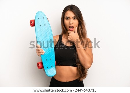 asian young woman with mouth and eyes wide open and hand on chin. skate board concept