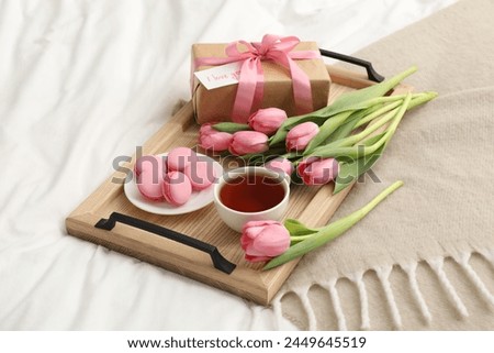 Tasty breakfast served in bed. Delicious macarons, tea, flowers, gift box and card with phrase I Love You on tray