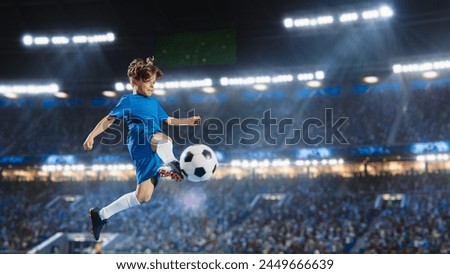 Aesthetic Shot Of Athletic Child Soccer Football Player Jumping And Kicking Ball Mid-Air On Stadium WIth Crowd Cheering. Young Boy Scoring a Goal on Junior World Championship Tournament Match. Royalty-Free Stock Photo #2449666639