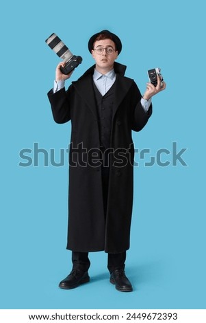 Male spy with photo cameras on blue background