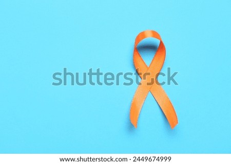 Orange ribbon on blue background. Multiple Sclerosis Awareness Month Royalty-Free Stock Photo #2449674999