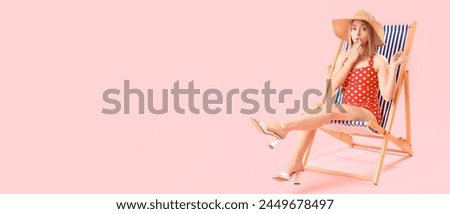 Surprised young woman sitting on deck chair against pink background with space for text