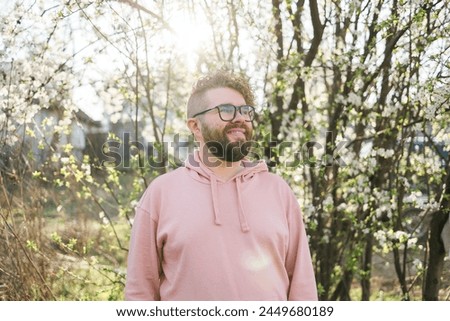 Handsome man outdoors portrait on background cherry blossoms or apple blossoms. Millennial generation guy and new masculinity concept Royalty-Free Stock Photo #2449680189