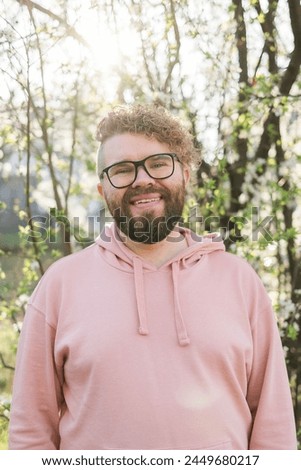 Handsome man outdoors portrait on background cherry blossoms or apple blossoms. Millennial generation guy and new masculinity concept Royalty-Free Stock Photo #2449680217