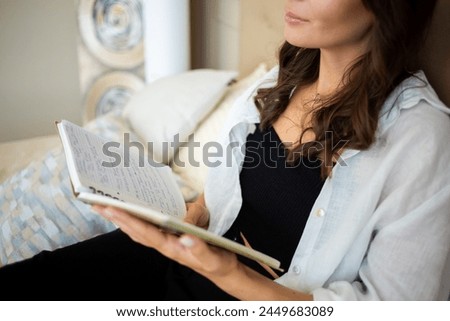The picture captures a girl with a book, her hands wrapped around it, savoring a moment of warmth and comfort. 