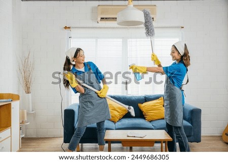 Vacuum guitar fun, Asian maid playful routine husband humor evident. Singing dancing joyfully. Music-filled service brings excitement to household cleaning. Cleaning is fun Royalty-Free Stock Photo #2449686305