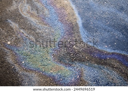 Oil rainbow gasoline spill on asphalt. Rainbow stains of oil and gasoline Royalty-Free Stock Photo #2449696519